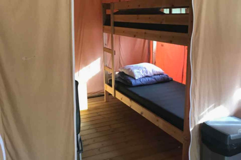 Interior of a luxury safari tent on Ameland in the Netherlands featuring bunk beds and wood flooring.