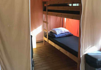 Interior of a luxury safari tent on Ameland in the Netherlands featuring bunk beds and wood flooring.