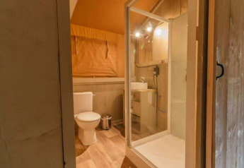 Bathroom in a luxury safari tent on Ameland, Netherlands, featuring a toilet, shower, and sink area.