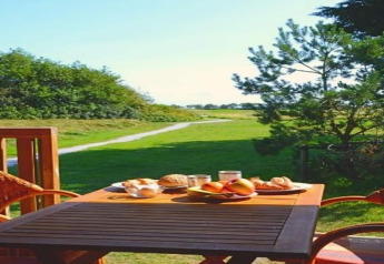 Udendørs spisebord med morgenmad, frugt og brød på terrassen af en luksus safaritelte på Ameland, Holland.