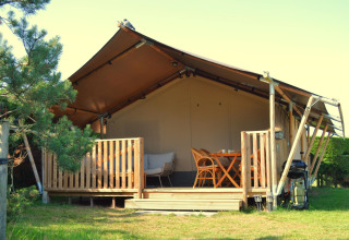 Außenansicht eines luxuriösen Safarizelts auf Ameland, Niederlande, mit Holzterrasse und Sitzmöbeln.