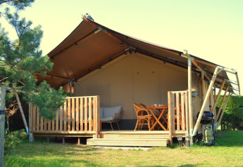 Outdoor view of a luxury safari tent on Ameland in the Netherlands, featuring a wooden deck and seating.