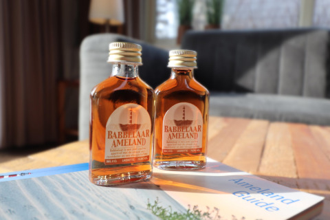 To flasker Babbelaar Ameland likør på et sofabord i en luksus safaritelte på Ameland, Holland.