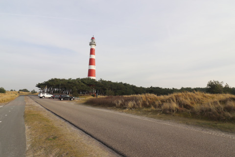 Tienda de safari de lujo en Ameland, Países Bajos. Faro rojo y blanco junto a dunas y carretera.