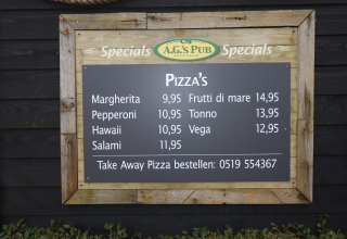 A.G.'s Pub menu board listing different pizza types and prices, photographed at a luxury safari tent on Ameland.
