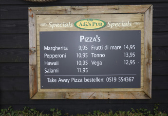 Cartel del menú de A.G.'s Pub con tipos de pizza y precios, fotografiado en una tienda safari de lujo en Ameland.