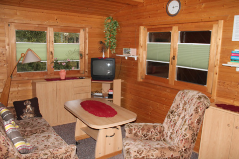 Gezellige woonkamer met houtbekleding en bloemenstoelen in de chalet By Ostseebad Rerik in Duitsland.