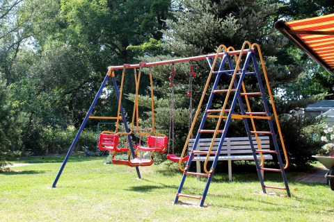 Parco giochi con altalena e panchina in un giardino verde presso una baita vicino a Ostseebad Rerik, Germania.