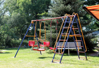 Speeltuin met schommel en bankje in groene tuin aan een chalet nabij Ostseebad Rerik, Duitsland.