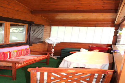 Houten veranda met gezellige zitplaatsen, tafel en ventilator bij een chalet nabij Ostseebad Rerik.