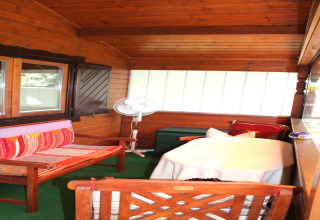 Houten veranda met gezellige zitplaatsen, tafel en ventilator bij een chalet nabij Ostseebad Rerik.