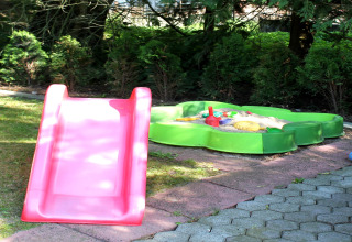 Area giochi per bambini con scivolo e sabbiera vicino a una baita presso Ostseebad Rerik, Germania.