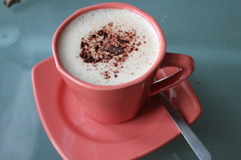 Een kop cappuccino met schuim en cacao, geserveerd in een roze kop bij By Ostseebad Rerik, Duitsland.