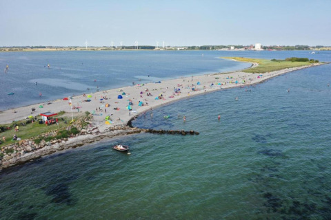 Spiaggia a By Ostseebad Rerik, Germania, con bagnanti, tende colorate e una barca sull'acqua blu.