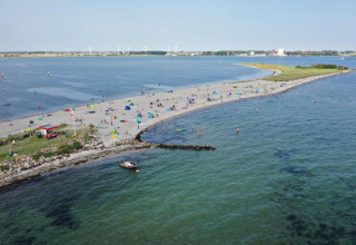 Zicht op het strand bij By Ostseebad Rerik in Duitsland, met badgasten, tenten en een boot op zee.