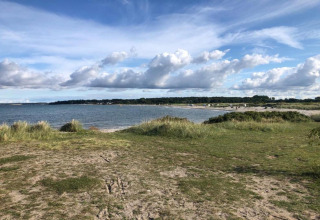 Vista sulla spiaggia e sul mare presso Ostseebad Rerik in Germania, con erba e cielo nuvoloso.