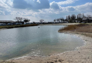 Kleine vijver bij hutten en caravans in de buurt van Ostseebad Rerik, Duitsland, met bewolkte lucht.