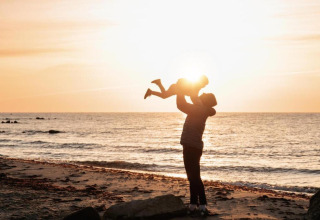 Sagoma di un adulto che solleva un bambino sulla spiaggia al tramonto vicino a Ostseebad Rerik, Germania
