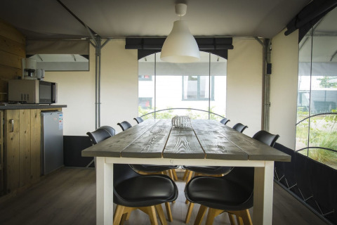 Eettafel met stoelen in een moderne safaritent bij Recreatiepark Duinhoeve 7, Nederland.
