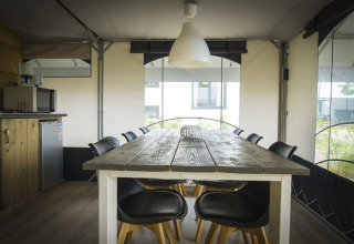 Dining table and chairs inside a modern safari tent at Recreation park Duinhoeve 7, Netherlands.