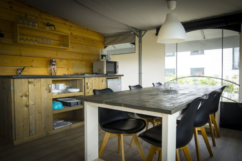Cocina y comedor de tienda safari con muebles de madera en el parque recreativo Duinhoeve 7, Países Bajos.