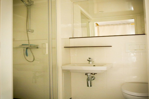Baño en una tienda de safari en Recreation park Duinhoeve 7, Países Bajos, con ducha, lavabo y espejo.