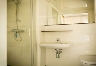 Bathroom in a safari tent at Recreation park Duinhoeve 7 in the Netherlands, featuring a shower and sink.
