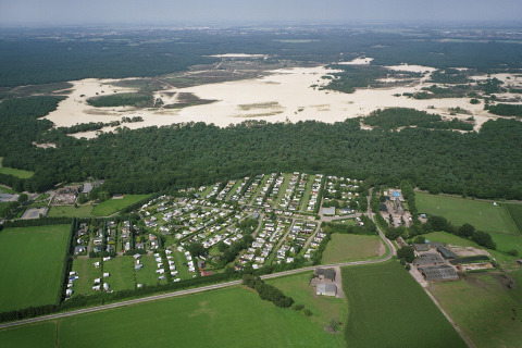 Vista aérea del parque recreativo Duinhoeve 7 en los Países Bajos, rodeado de campos, bosque y dunas.