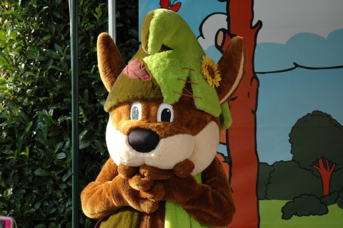 A person in an animal costume with a green hat and flower stands at Recreation park Duinhoeve 7, Netherlands.