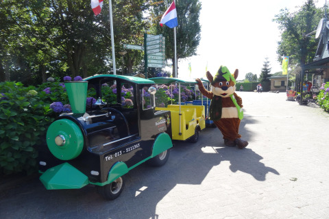 Petit train et mascotte costumée au parc de loisirs Duinhoeve 7, Pays-Bas, sous un ciel ensoleillé.