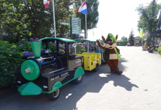 Tren infantil y mascota disfrazada en el parque recreativo Duinhoeve 7, Holanda, día soleado.