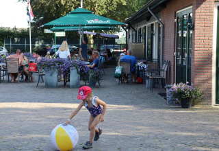 Una niña juega con una pelota de playa cerca de una cafetería al aire libre en el safari Duinhoeve 7 de los Países Bajos.
