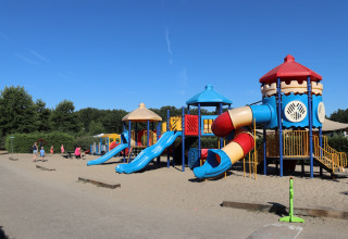 Terrain de jeux coloré avec toboggans et tours par une journée ensoleillée au parc Duinhoeve 7, Pays-Bas.