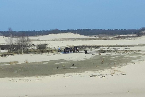 Vista de dunas de arena con un grupo de personas y caballos en Recreation Park Duinhoeve 7, Países Bajos.