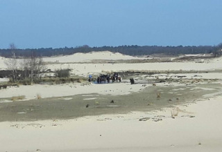 View of sandy dunes with a group of people and horses at Recreation Park Duinhoeve 7 in the Netherlands.