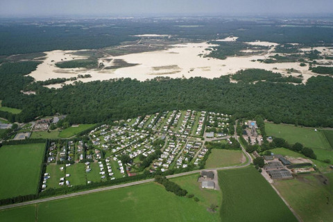 Luftfoto af Recreation park Duinhoeve 7 i Holland, med skov, sandklitter og campingvogne synlige.