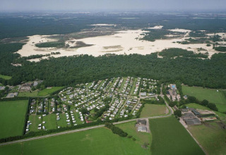 Luftfoto af Recreation park Duinhoeve 7 i Holland, med skov, sandklitter og campingvogne synlige.
