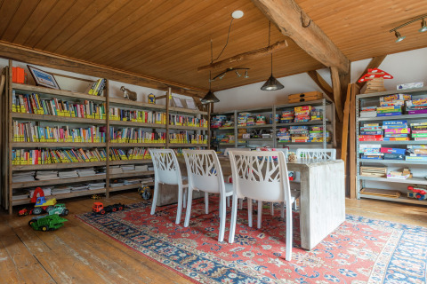 Foto di una stanza lodge accogliente con scaffali di libri, giochi da tavolo, giocattoli e tavolo rustico.