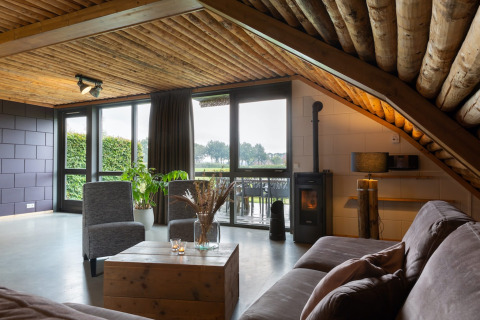 Accogliente soggiorno al lodge Koe in de Kost 3 nei Paesi Bassi, soffitto in legno e grandi finestre.