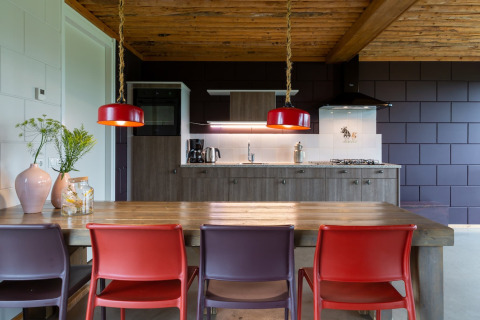 Cucina moderna di lodge con soffitto in legno, sedie colorate e lampade a sospensione rosse nei Paesi Bassi.