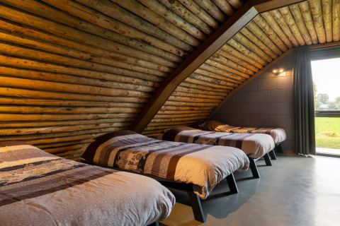 Interno camera nella lodge Koe in de Kost 3 nei Paesi Bassi con quattro letti e pareti in legno.