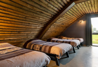 Interno camera nella lodge Koe in de Kost 3 nei Paesi Bassi con quattro letti e pareti in legno.