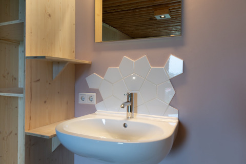 Moderne wastafel met unieke witte zeshoekige tegels en houten planken bij Koe in de Kost 4, Nederland.