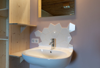 Moderne wastafel met unieke witte zeshoekige tegels en houten planken bij Koe in de Kost 4, Nederland.