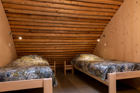 Twee eenpersoonsbedden met kleurrijke dekbedden in een knusse houten kamer van Koe in de Kost 4 in Nederland.