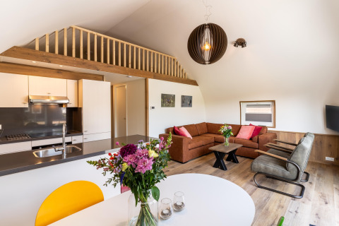 Modern living room and kitchen at 't Landgoed Baars 1 lodge, featuring flowers and cozy decor in the Netherlands.