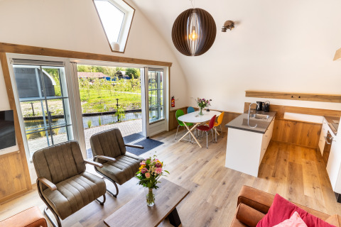 Bright modern living area at 't Landgoed Baars 1 lodge in the Netherlands, with garden view and open kitchen.