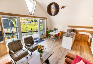 Bright modern living area at 't Landgoed Baars 1 lodge in the Netherlands, with garden view and open kitchen.