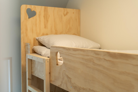 Top view of a wooden bunk bed with pillows and heart cutouts in a room at 't Landgoed Baars 1 lodge.