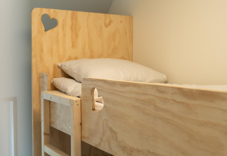 Top view of a wooden bunk bed with pillows and heart cutouts in a room at 't Landgoed Baars 1 lodge.